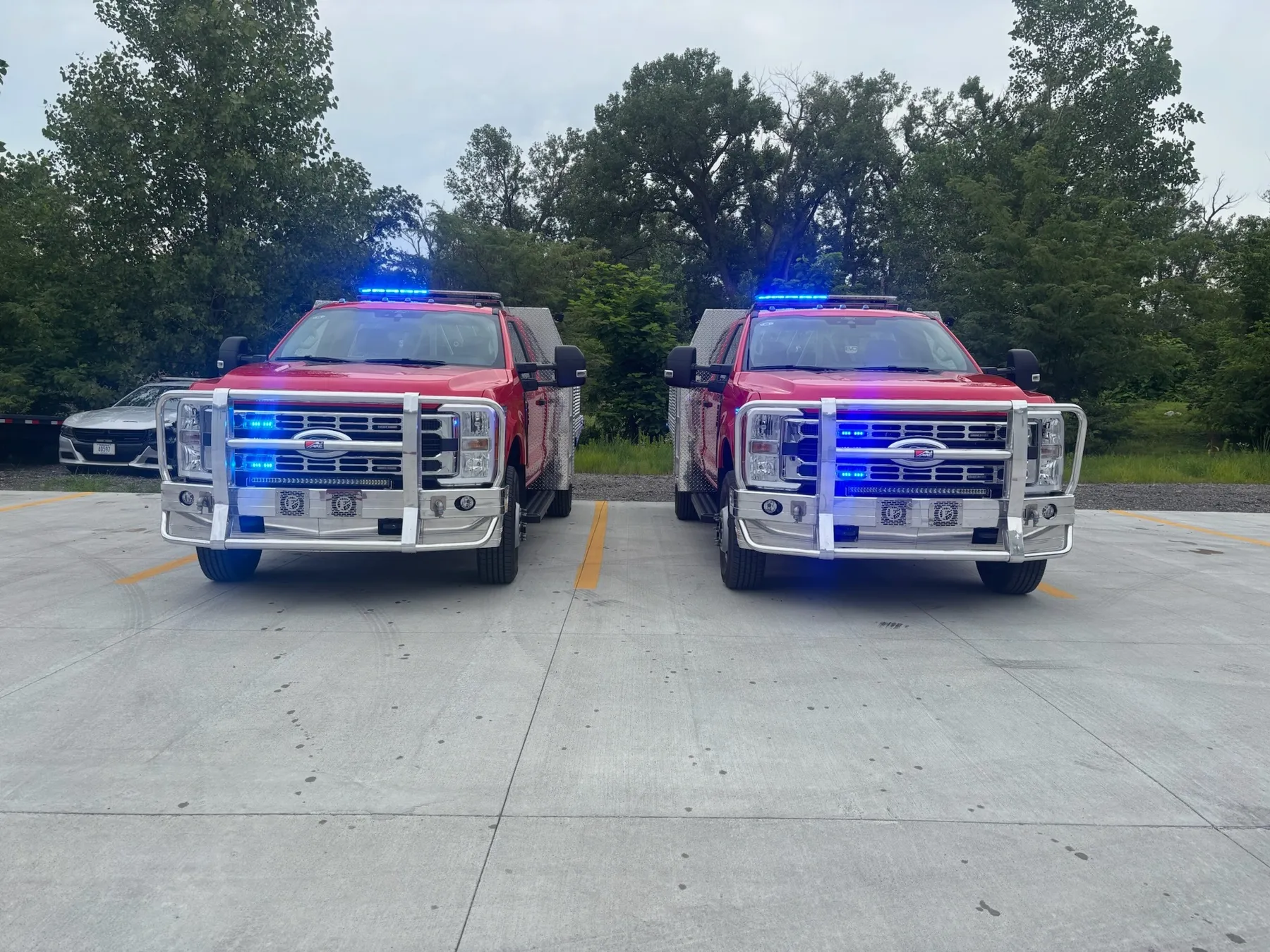 Pair of red fire rescue trucks with emergency warning lights activated, outfitted by Elite Vehicle Outfitters