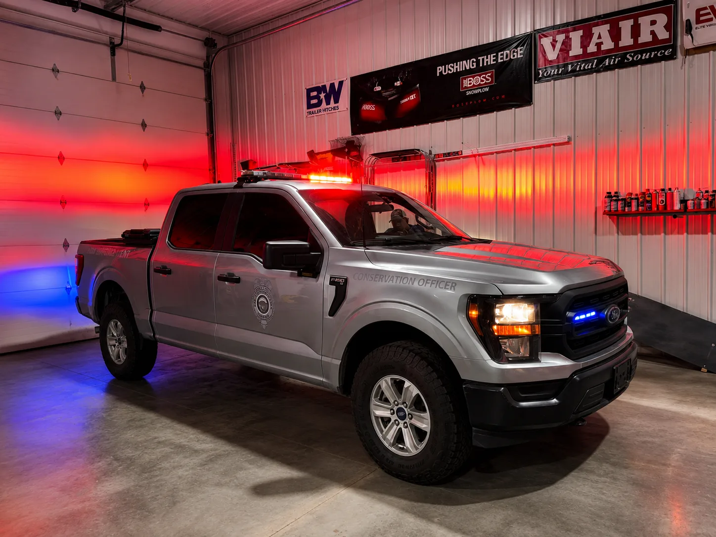 Silver Ford F-150 Conservation Officer truck with red and blue emergency lighting, built by Elite Vehicle Outfitters in their Waterloo, Nebraska shop